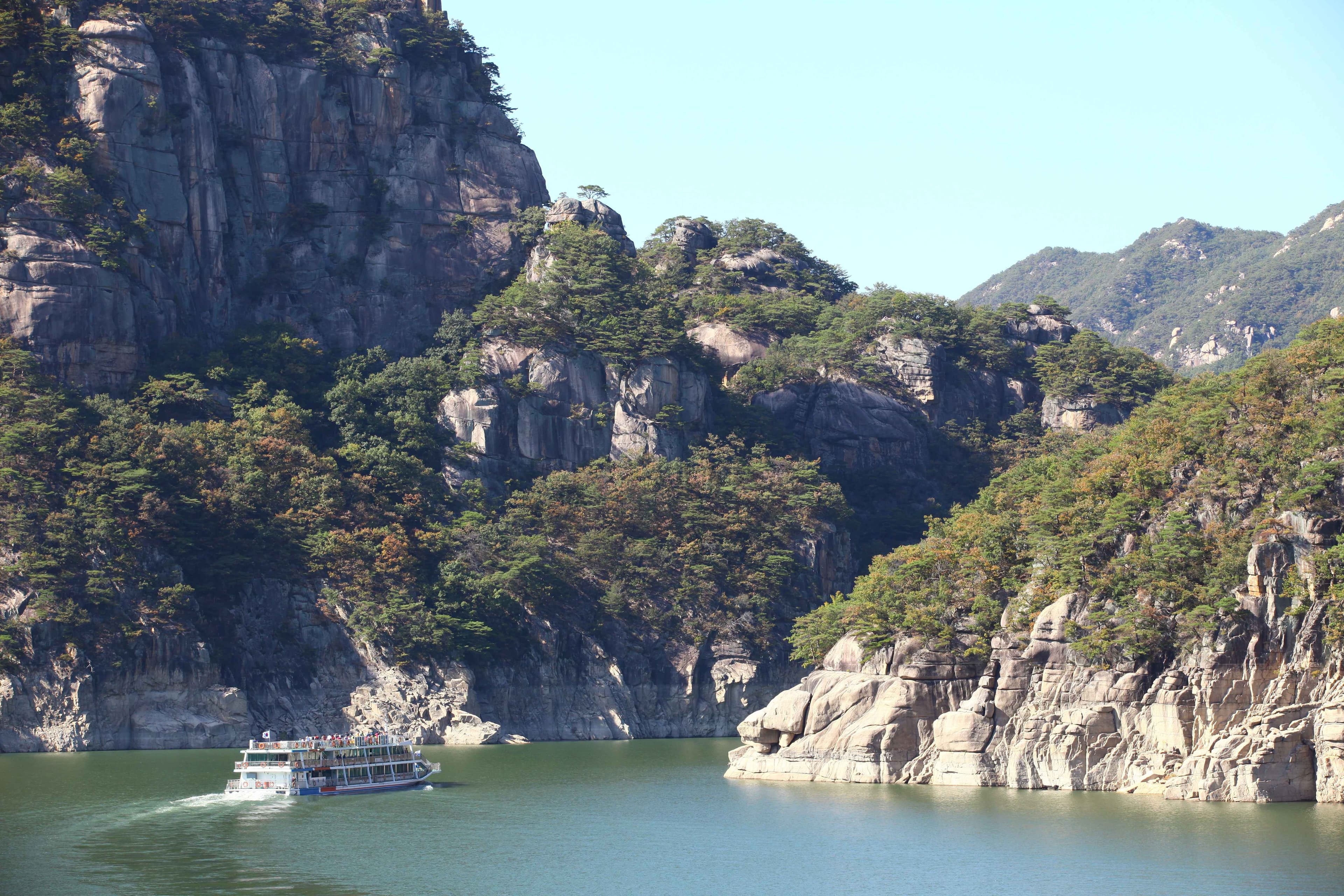 A cruise boat on green water beneath limestone cliffs at Chungjuho in Danyang.